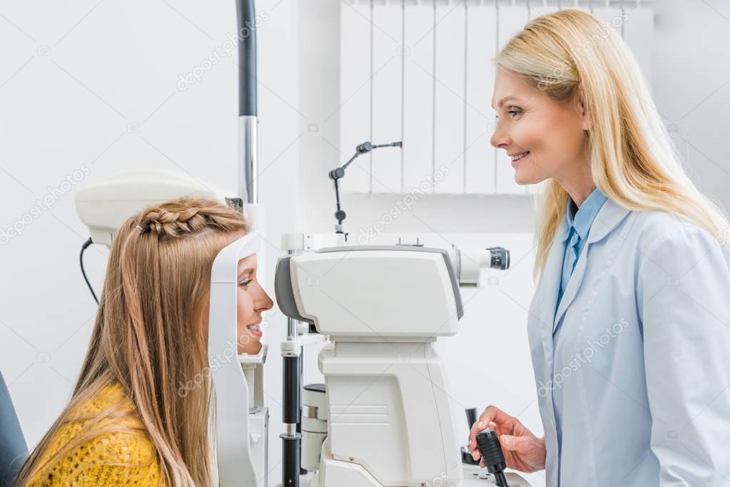 professional female optometrist examining patient through slit lamp in clinic