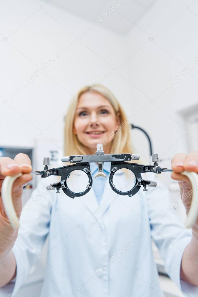 optician in white coat holding trial frame in clinic