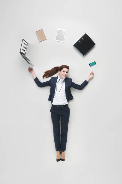 overhead view of businesswoman with various office supplies using laptop isolated on grey