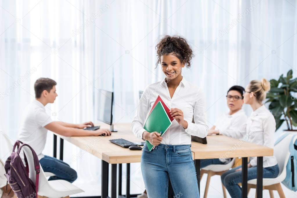 young happy african american student girl in classroom with friends