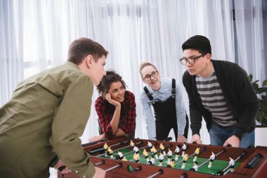 happy young teenagers playing in table soccer clipart