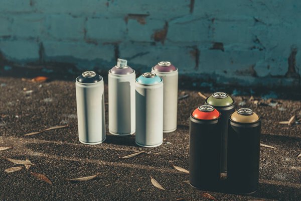 cans with colorful spray paint for graffiti on asphalt