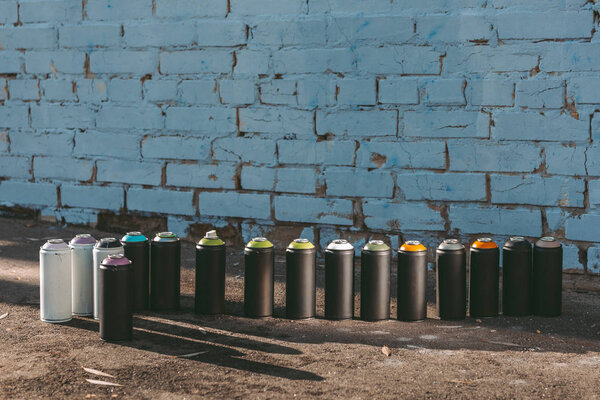 cans with colorful spray paint standing in row on asphalt