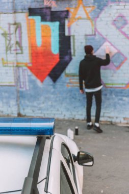 arkadan görünüşü vandal boyama grafiti duvar, polis arabasının ön plan üzerinde
