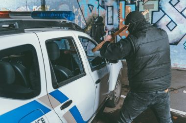 vandal crashing police car with baseball bat while another man painting graffiti on wall clipart