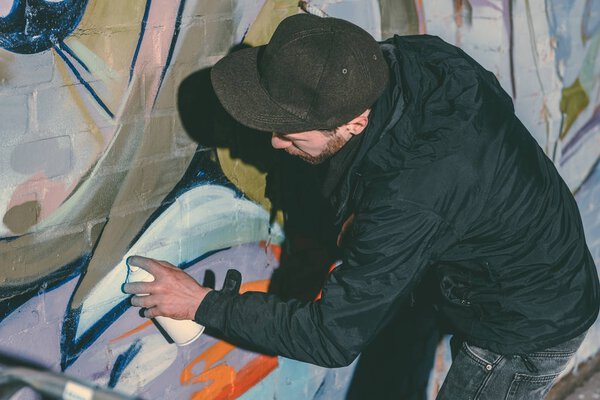 street artist painting colorful graffiti on wall of building at night