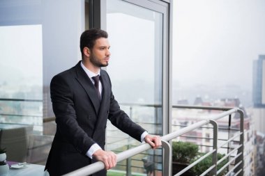 takım elbise ayakta balkon, genç dalgın adam portresi