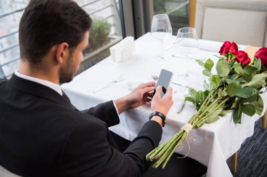 restoranda kız için beklerken smartphone kullanarak takım elbiseli adam yan görünüm