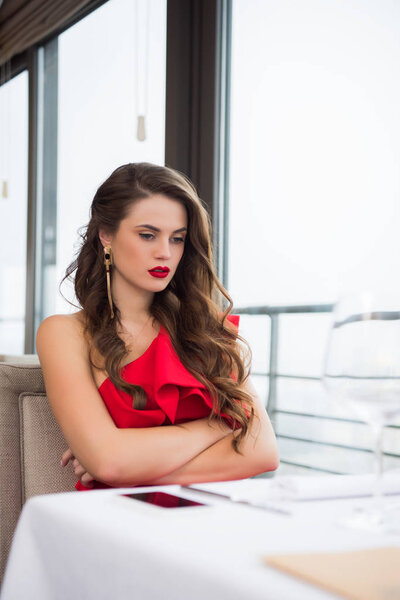 upset woman with arms crossed waiting for boyfriend on date in restaurant