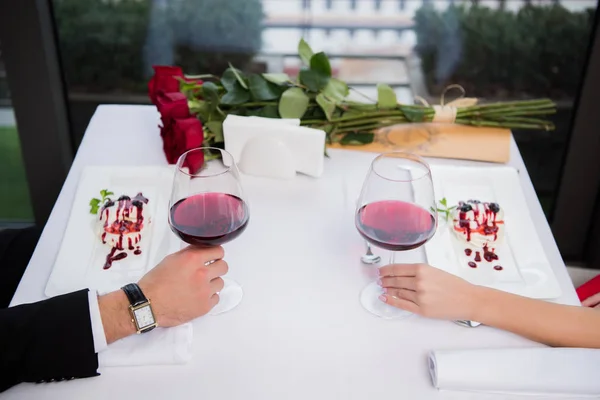 聖バレンタインの日にレストランでテーブルに座って赤ワインのグラスのカップルの部分的なビュー — ストック写真