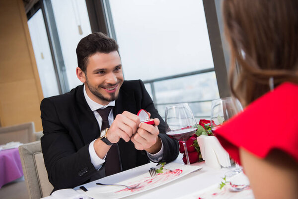 partial view of smiling man proposing to girlfriend on romantic date in restaurant on st valentine day