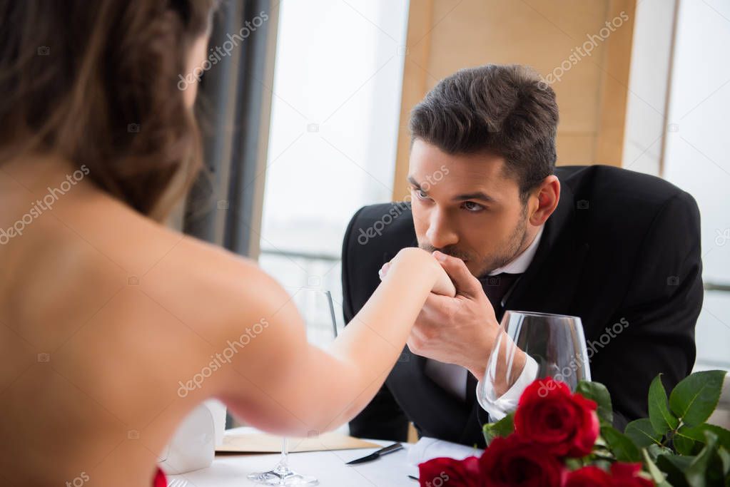 partial view of man kissing girlfirend hand on romantic date in restaurant, st valentine day