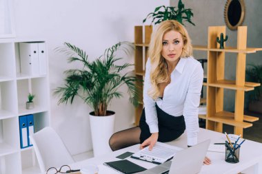 masada oturan ve kameraya bakarak baştan çıkarıcı kadın