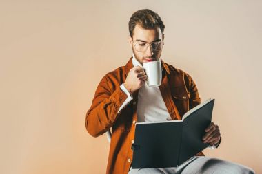 elinde defter okurken içme kahve bej üzerinde izole odaklı adam portresi