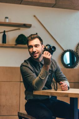 adam el kafede masada oturan fotoğraf makinesi ile gülümseyen portresi