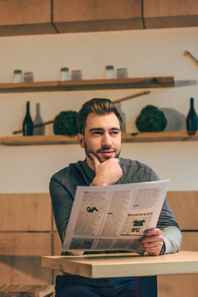 カフェのテーブルで新聞を読みながらよそ見物思いにふけるビジネスマンの肖像画 — ストック写真