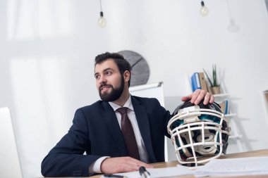 young businessman with rugby helmet at workplace in office clipart