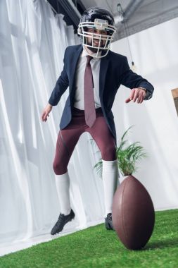 businessman in rugby helmet playing american football in office clipart
