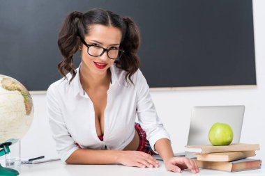 workdesk yazı tahtası önünde oturan genç seksi öğretmen
