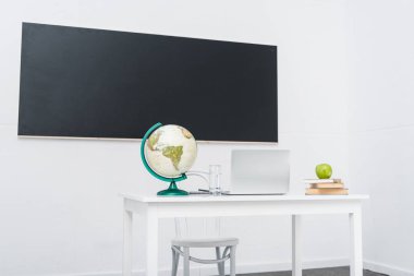 teachers desk in classroom in front of chalkboard clipart