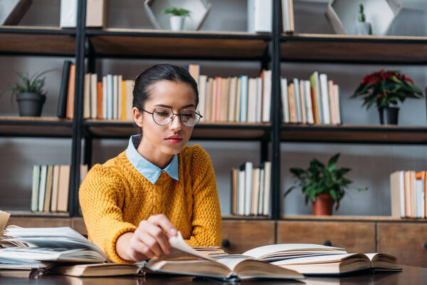 young student girl preparing for exam at library and reading book