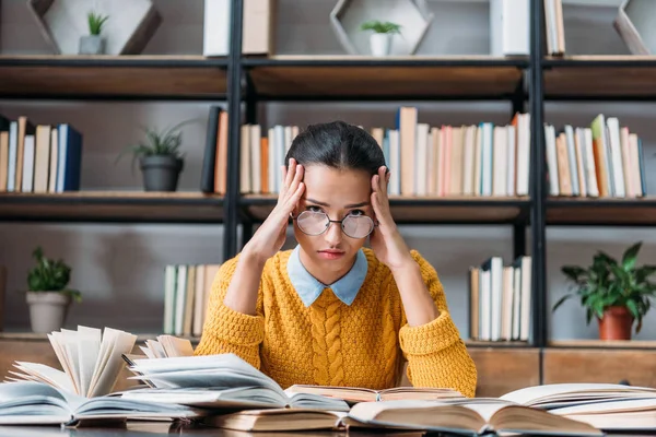 Zmęczony Student Dziewczyna Przygotowuje Się Egzaminu Bibliotece Trzymając Głowę Rękami — Zdjęcie stockowe