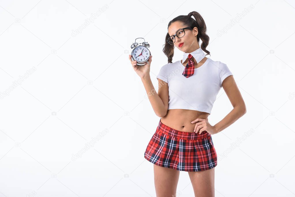 sceptic sexy schoolgirl looking at alarm clock isolated on white