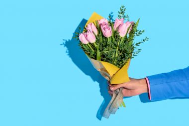 partial view of african american man holding bouquet of flowers on blue background clipart