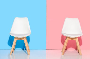 close up view of white chairs against blue and pink wall clipart