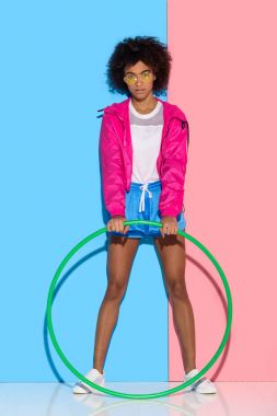 Woman in sportswear standing with hoop on pink and blue background  clipart
