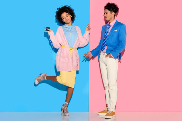 Young couple having fun on pink and blue background