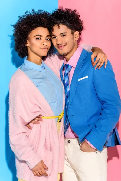 fashionable young couple hugging each other on pink and blue background