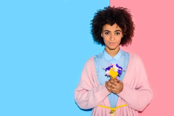 Aantrekkelijke Afrikaanse Meisje Permanent Met Bloemen Handen Roze Blauwe Achtergrond — Stockfoto