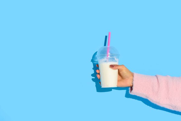 частичный взгляд на африканскую американку, держащую стакан молока с соломой на синем фоне
