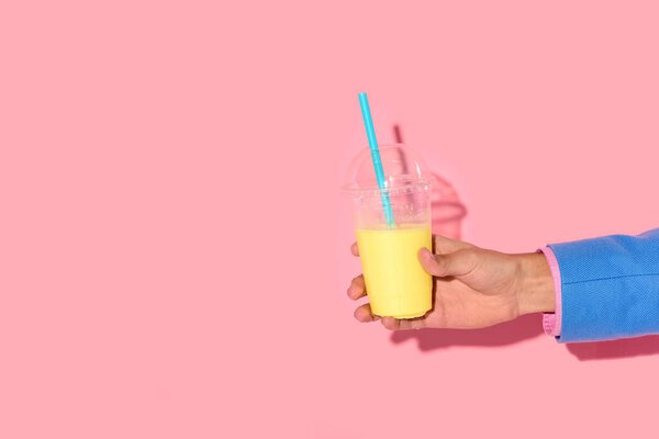 Обрезанный снимок африканского американца, держащего стакан сока на розовом фоне
