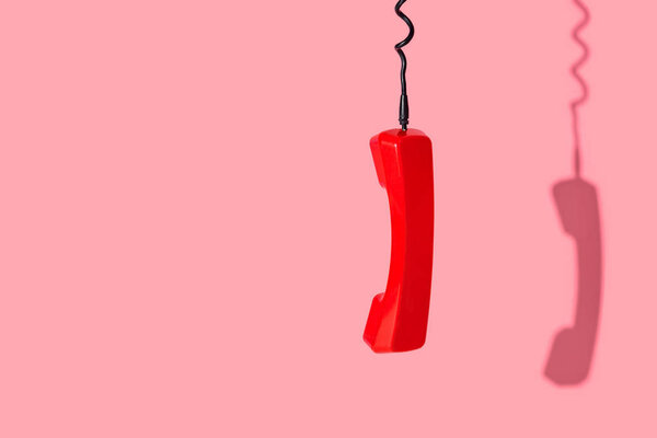 View of old telephone handset on pink background