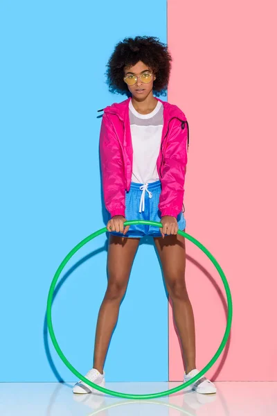 穿运动服的女子站在粉红色和蓝色的背景箍 — 图库照片