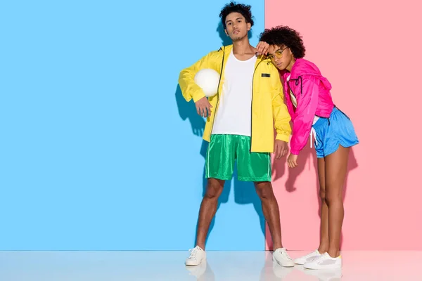 有吸引力的年轻夫妇在运动服站立反对粉红色和蓝色背景 — 图库照片