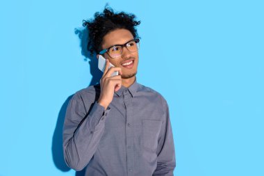 Mavi arka plan telefonla konuşurken genç Afrika amercian işadamı 