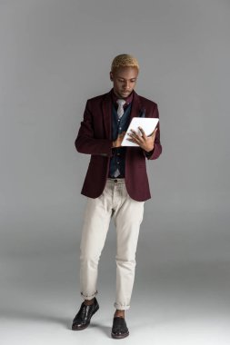 Afrika kökenli Amerikalı adam gri arka plan üzerinde dijital tablet kullanma  