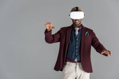 Afrika kökenli Amerikalı adam gri arka plan üzerinde uzanmış kollu VR gözlük kullanma    
