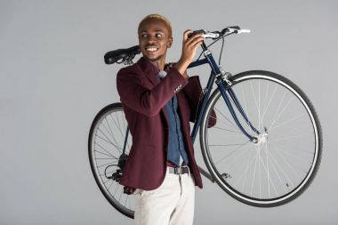Afrika kökenli Amerikalı adam Bisiklet gri izole elinde tutan gülümseyerek  