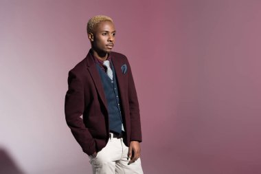 Afrika delikanlı kırmızı ceket ayakta el cep pembe bir arka plan ile    