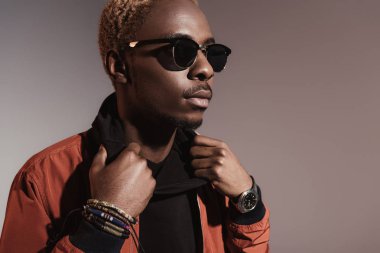 Şık genç Afro-Amerikan adam ceketinin üzerinde ışık arka plan izole düzeltiyor