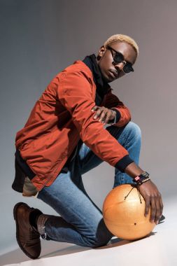 Katta ve kameraya bakarak basketbol topu tutan şık genç Afro-Amerikan adam