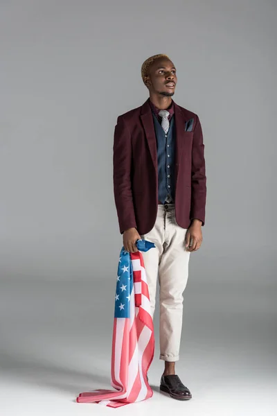 アメリカの国旗を手に灰色の背景に上方への検索でアフリカ系アメリカ人  — 無料ストックフォト