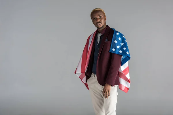 african american man with american flag on shoulders  looking at camera isolated on grey