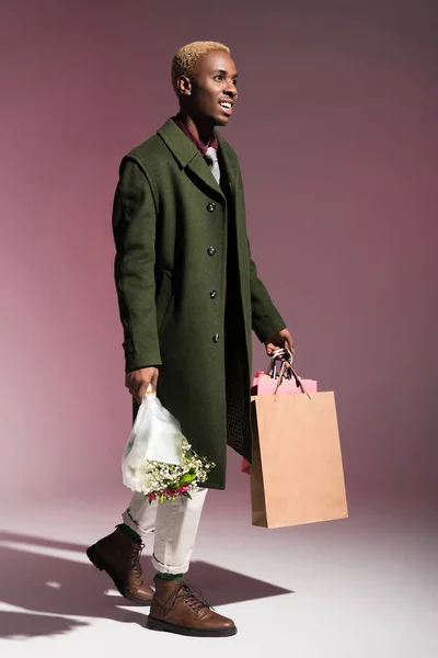 时尚的年轻的非洲裔美国人散步和携带鲜花和购物袋的花束 — 图库照片