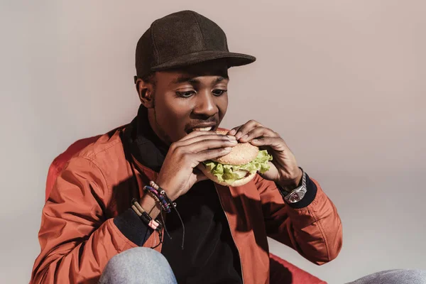 Młody Mężczyzna African American Jedzenie Hamburgerów Szarym Tle — Zdjęcie stockowe