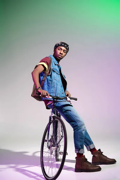 时尚的年轻的非洲裔美国人坐在自行车上 看着灰色 — 图库照片